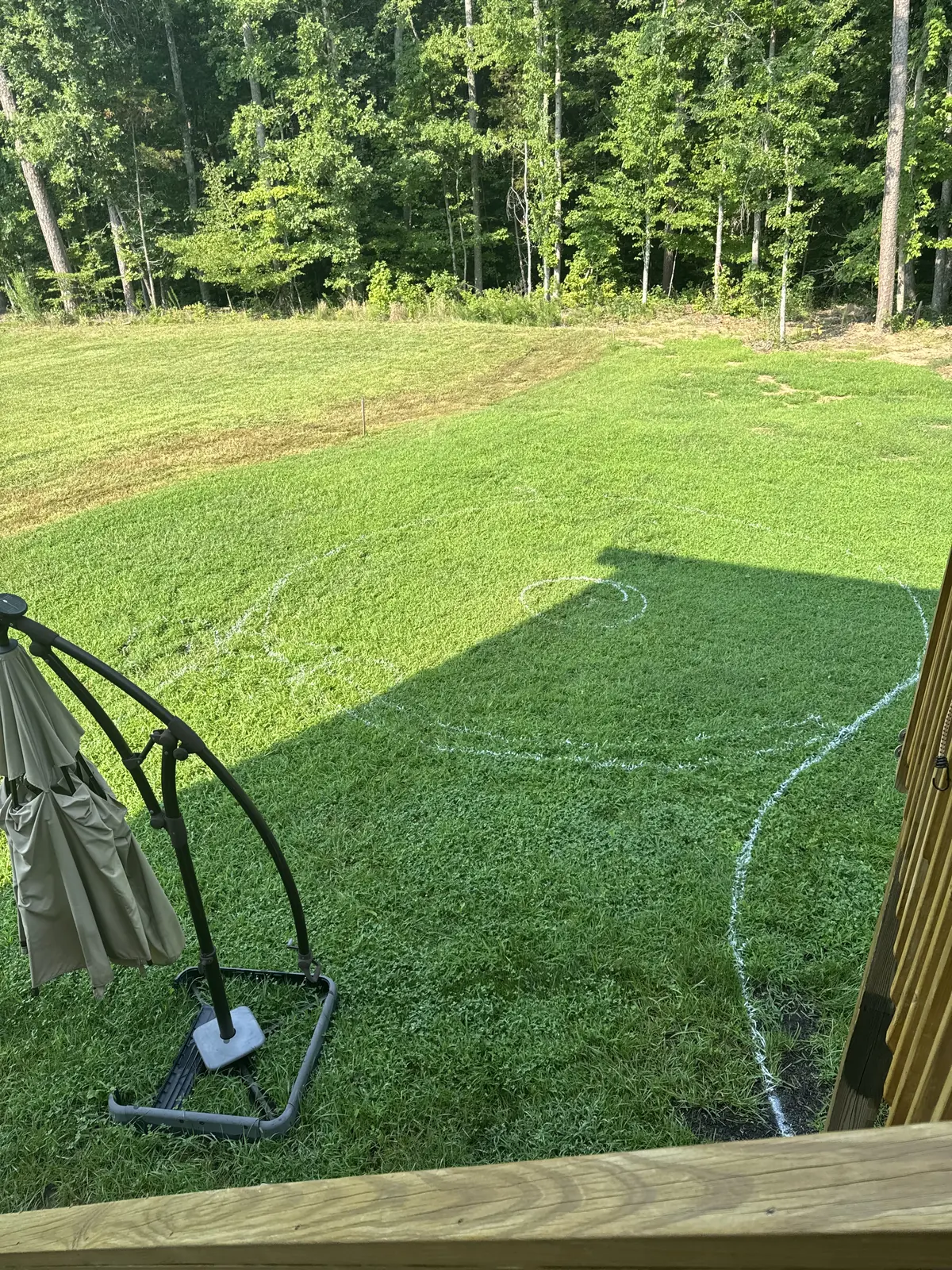 Backyard lawn marked with paint layout before paver patio installation, Kernersville NC
